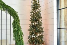 a lovely skinny Christmas tree decorated with a bow, silver ornaments and lights is a nice addition to a staircase