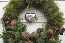 a natural Christmas wreath of moss, greenery, foliage, nuts, acorns, pinecones and a silver heart