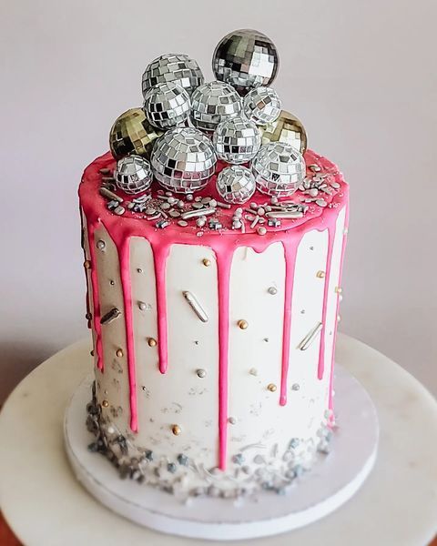 a party cake with sprinkles, pink drip and silver and gold disco balls on top is awesome for NYE