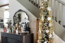 a pencil Christmas tree with lights and white ornaments is a cool and delcate decoration for Christmas