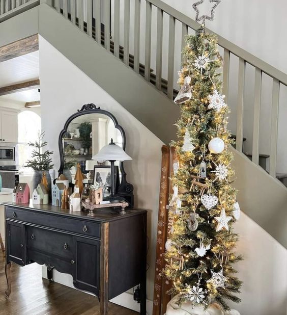 a pencil Christmas tree with lights and white ornaments is a cool and delcate decoration for Christmas