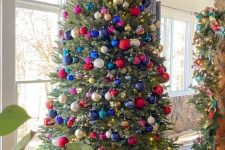 a pretty Christmas tree decorated with colorful ornaments of various sizes and shades is amazing