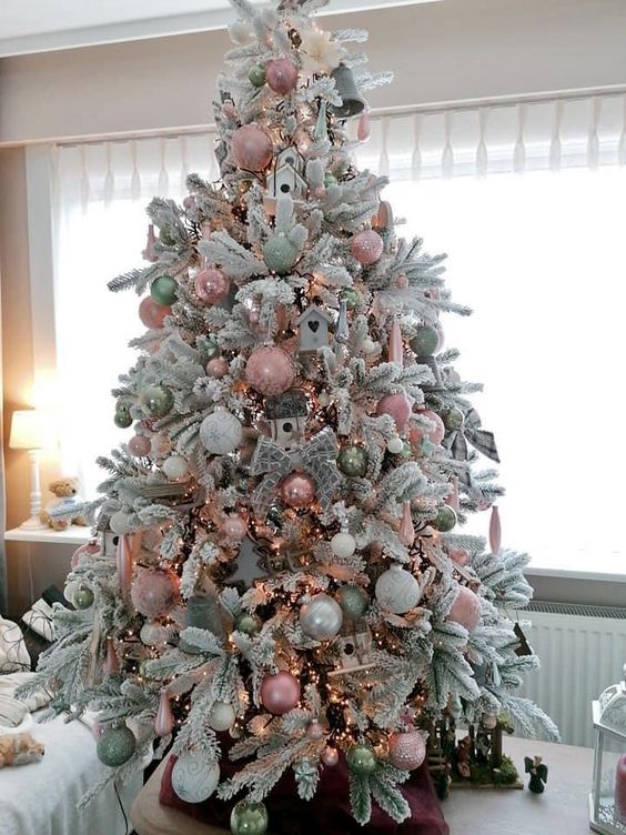 a pretty flocked Christmas tree with pastel pink, green and pearly ornaments, bows, bird houses and lights