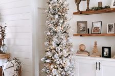 a pretty flocked pencil Christmas tree decorated with branches, lights and silver and white ornaments