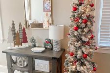 a pretty traditional flocked Christmas tree with lights and plaid ribbons plus red ornaments is a stylish holiday decor idea