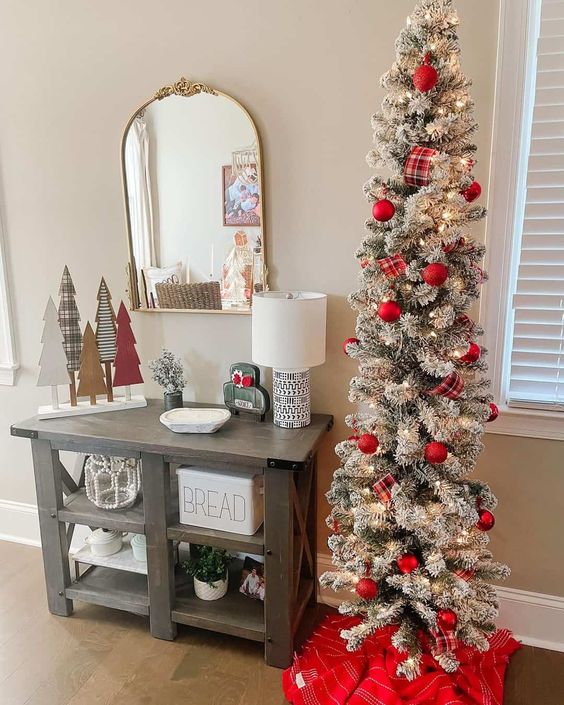 a pretty traditional flocked Christmas tree with lights and plaid ribbons plus red ornaments is a stylish holiday decor idea
