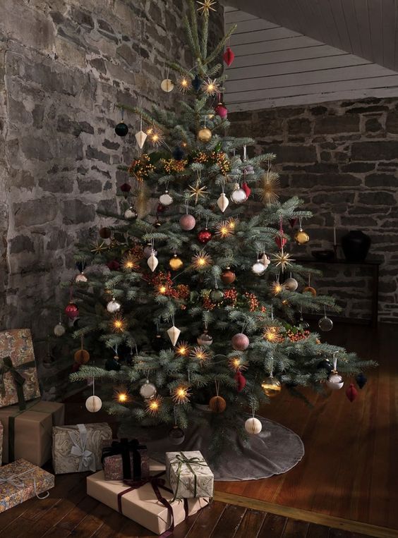 a refined Christmas tree decorated with neutral paper ornaments, gold stars, silver, red and brown ornaments