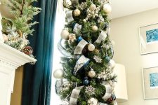 a refined slim Christmas tree styled with plaid ribbon, silver and navy ornaments and snowflakes