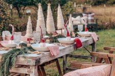 a rustic Christmas tablescape with evergreens, faux Christmas trees, red and striped napkins and mini gnomes in each place setting