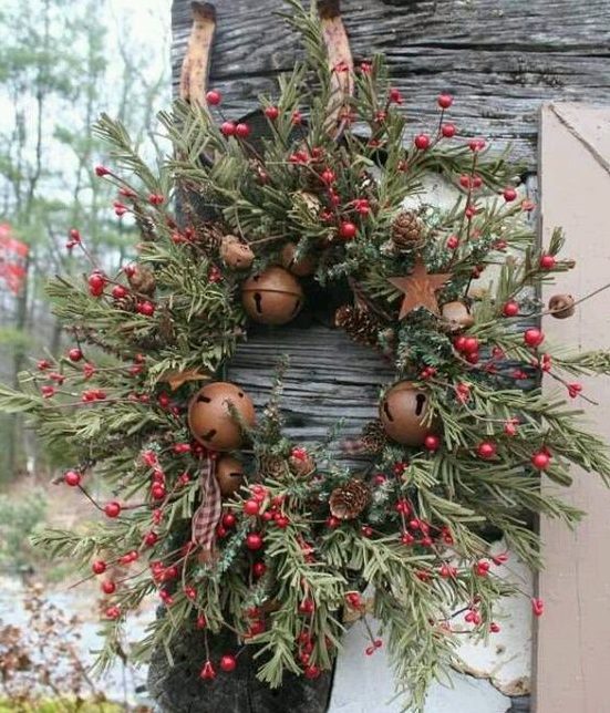 a rustic Christmas wreath of evergreens, berries, pinecones and large bells looks bold, beautiful and very chic