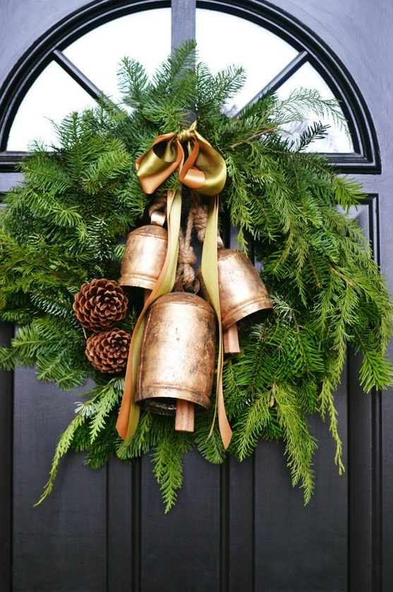 a rustic Christmas wreath of evergreens, pinecones, oversized bells and a silk bow on top is amazing