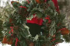 a rustic Christmas wreath of greenery, evergreens, berries, pinecones and magnolia leaves