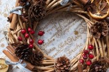 a rustic Christmas wreath of vine, pinecones, berries, cinnamon sticks, red stars and citrus slices is cozy and lovely