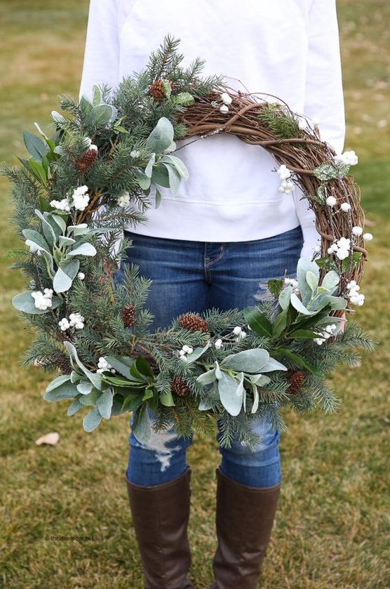 a rustic farmhouse Christmas wreath with evergreens, pinecones and foliage plus white berries is a cool decor idea