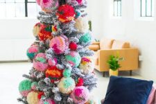 a silver Christmas tree decorated with colorful oversized pompoms for a bold statement