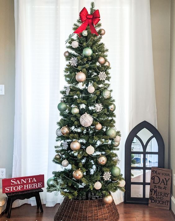 a skinny Christmas tree styled with neutral and light green ornaments, beads, snowflakes and a bead garland