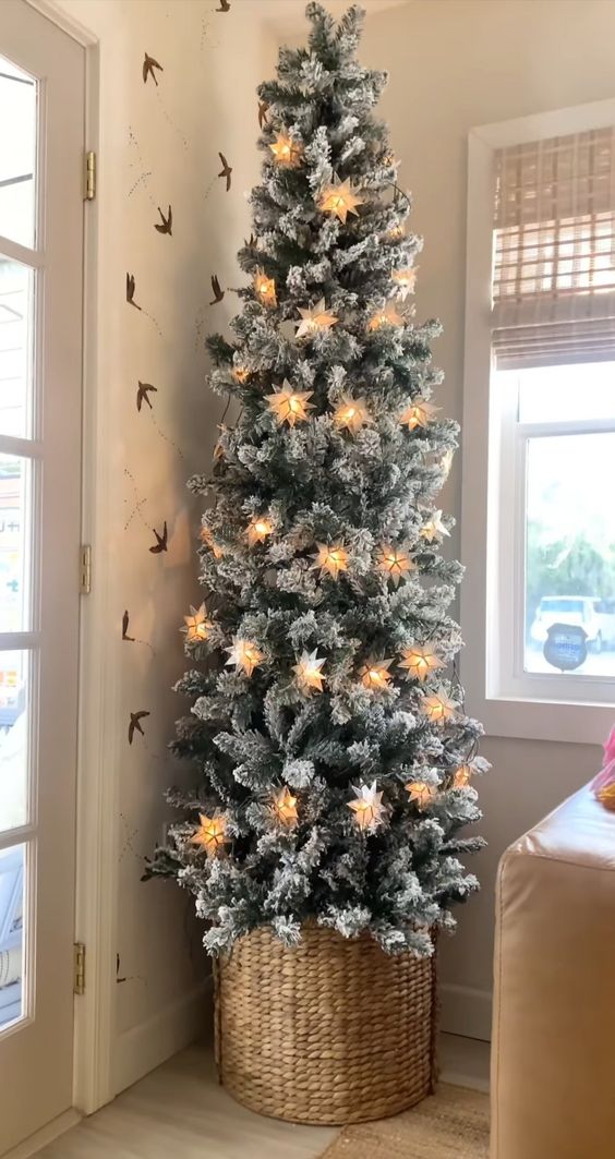 a skinny flocked Christmas tree with star-shaped lights in a basket is a very cool and catchy idea, no need for ornaments