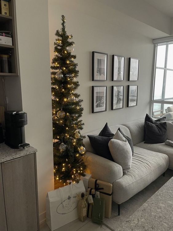 a slim Christmas tree decorated with lights and silver ornaments is a stylish idea for a Scandinavian space