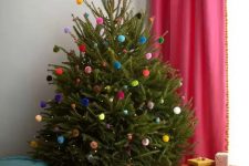 a small Christmas tree decorated with only lights and colorful pompoms is an amazing decor idea