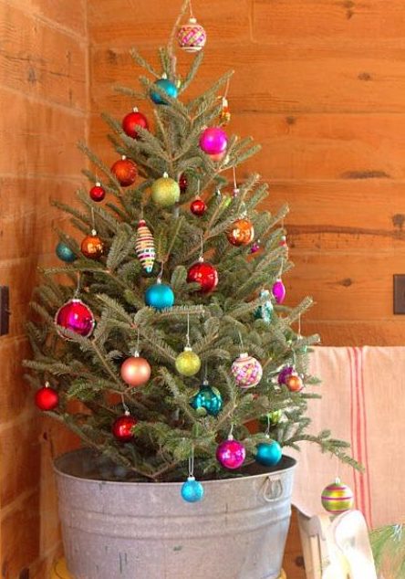 a small natural tree in a bucket decorated with colorful ornaments looks bold and eye-catching