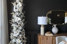 a sophisticated flocked pencil Christmas tree decorated with black ornaments, pampas grass and faux flowers