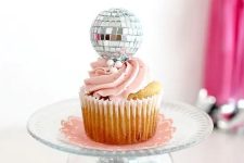 a stand of a bowl with disco balls, a sheer plate and a cupcake topped with a disco ball for a party feel