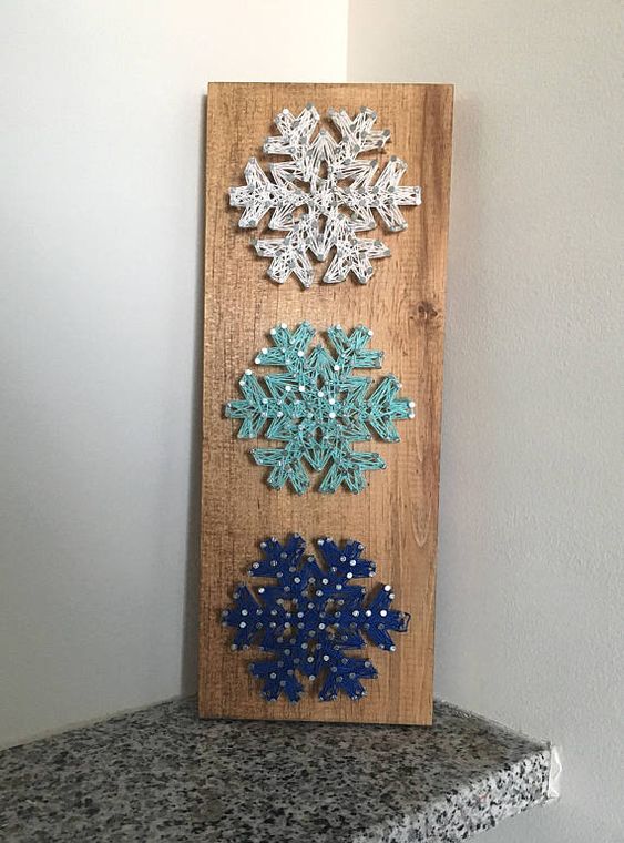 a stylish Christmas string art of a white, aqua and navy snowflakes si a cool and catchy decoration