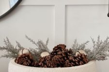 a textural white bowl with bells, pinecones and evergreens is a cool modern decor idea for the holidays