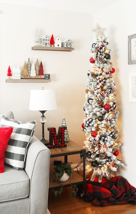a traditional skinny Christmas tree with plaid ribbon, lights, pinecones and red and black ornaments