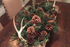 a vintage wooden dough bowl with evergreens, pinecones and antlers is a cool and cozy all-natural Christmas centerpiece