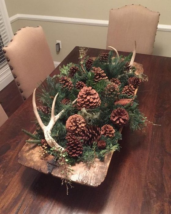 A vintage wooden dough bowl with evergreens, pinecones and antlers is a cool and cozy all natural Christmas centerpiece