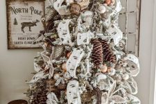 a vintage woodland flocked Christmas tree with lots of usual and snowy pinecones, ribbons, ornaments and vine wreaths is super cool