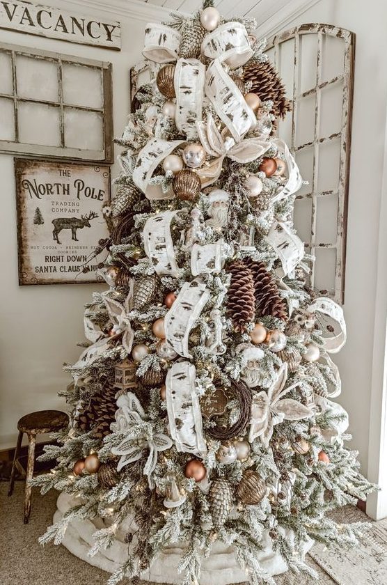 a vintage woodland flocked Christmas tree with lots of usual and snowy pinecones, ribbons, ornaments and vine wreaths is super cool