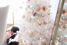 a white Christmas tree decorated with silver, gold, copper and blush ornaments and some faux blooms looks absolutely breathtaking