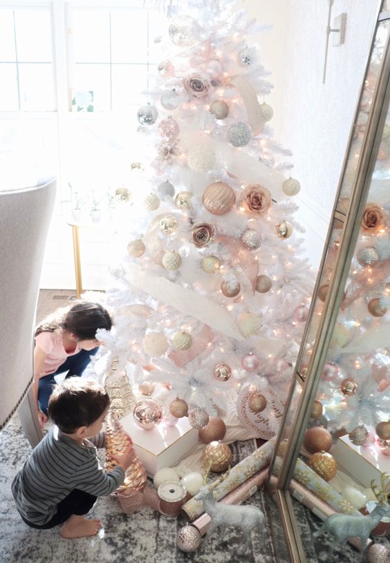 a white Christmas tree decorated with silver, gold, copper and blush ornaments and some faux blooms looks absolutely breathtaking