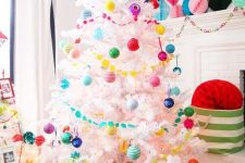 a white Christmas tree decorated with super bright ornaments and garlands, matching paper pompoms and a tree skirt