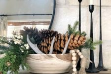 a woodland Christmas arrangement of a wooden bowl, evergreens, pinecones and wooden beads and antlers