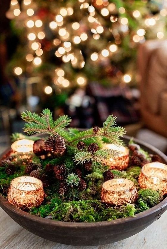 a woodland Christmas centerpiece of a wooden bowl, moss, pinecones and candles is a lovely piece you can make