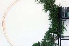 an oversized wreath with evergreens and some berries on one side looks very modern and minimalist