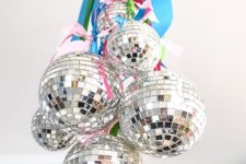 disco balls hanging on bright ribbons are amazing to style your space for NYE, hang them on a chandelier