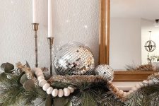 stylish NYE mantel decor with evergreens, beads and garlands plus some disco balls is cool