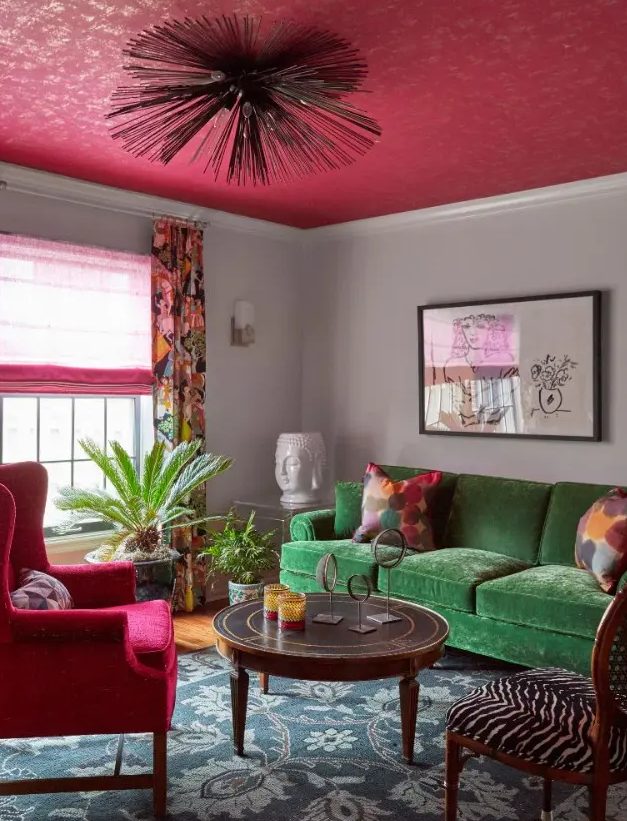 a catchy eclectic living room with a green sofa, a pink chair, curtain and a ceiling, a round table and a zebra print chair