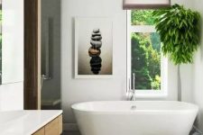 03 a contemporary home spa with a flaoting vanity, an oval tub, greenery and rocks and an artwork of balancing rocks