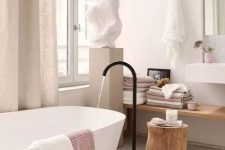 05 a lovely spa bathroom with an oval tub and a black faucet, a floating shelf, a wall-mounted sink and a sculpture on a stand