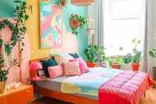 08 a colorful eclectic bedroom with an emerald accent wall, a red bed with colorful bedding, a bright artwork, potted plants, an orange credenza