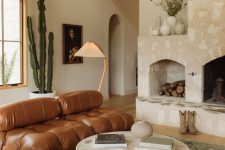 09 a beautiful earthy living room with a large stone hearth, a brown leather tufted sofa, a low coffee table, a green rug and plants