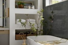 09 a mid-century modern bathroom with a window, a wall clad with black tiles, a wall with shelves, a tub and a stool