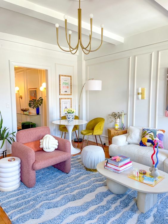 an eclectic living room with paneling, a white sofa, a pink chair, a coffee table and poufs, a small table and mustard chairs