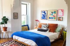 10 a catchy eclectic bedroom with a colorful gallery wall, a bed with bright bedding, a bold printed rug and some plants