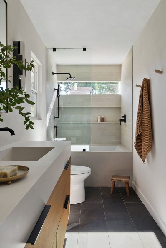 a tan bathroom clad with tiles, with a clerestory window, a shelf, a floating vanity with a sink and some hooks